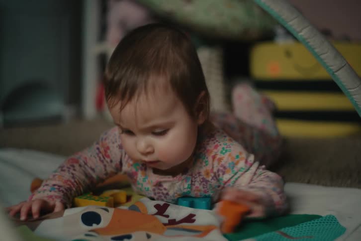 Baby lying on a rug putting toy pieces in his mouth