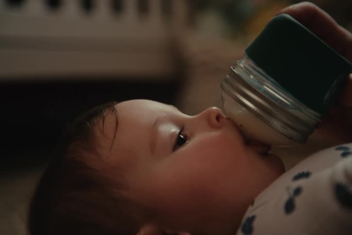 Baby lying down drinking milk from a bottle