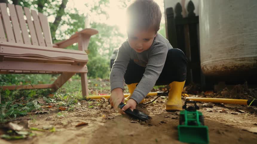 Little boy in yellow boots playing in the yard