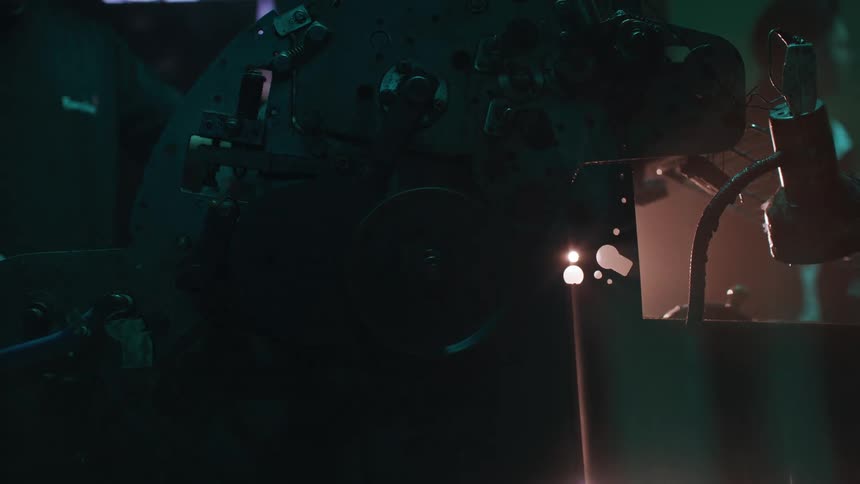 A large industrial machine glows under focused lighting