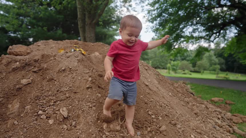 Boy climbing down a small mound of dirt in a natural area