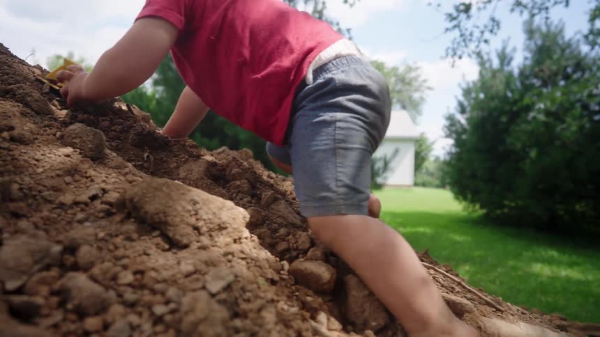 Boy climbing a mound of dirt in a garden