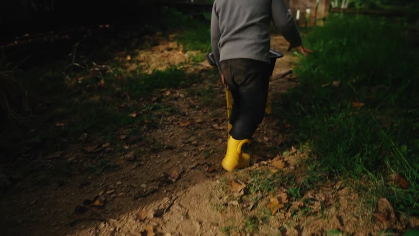 Boy in boots walking in a yard