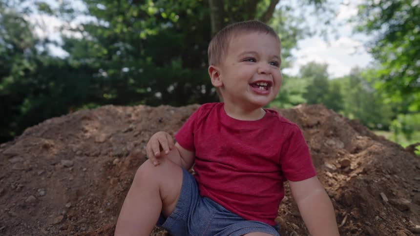 Smiling boy sitting on ground outdoors