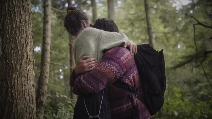 Two people are hugging in the forest