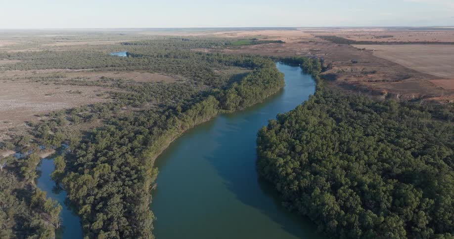 A winding river cuts through dense forest bordered by dry open plains