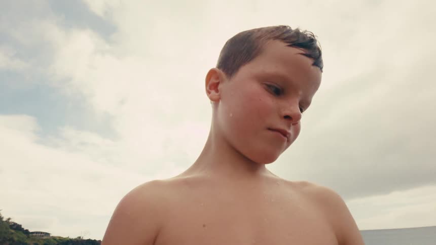 Shirtless boy with wet body in a seaside setting