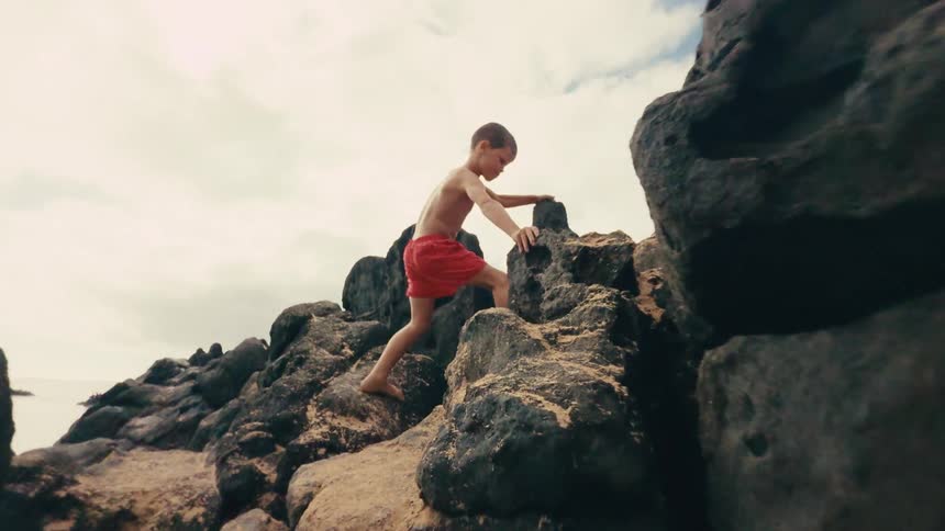 Boy climbing between rocks in a natural area