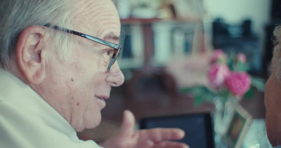 Elderly couple sitting interacting with a tablet