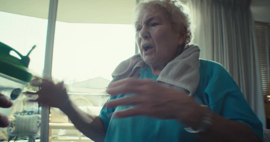 Sweaty elderly lady receiving a glass of water next to her cheerful husband