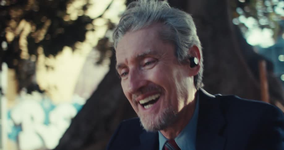 Man sitting outside on a video call is smiling and talking