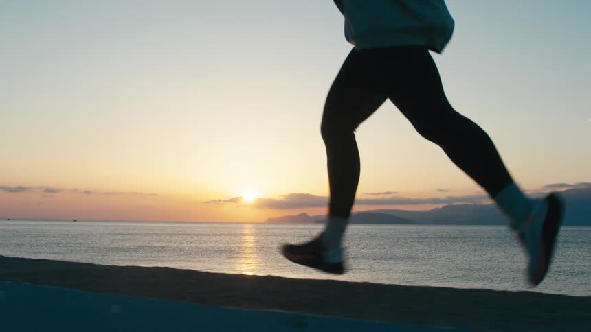 Person running along the coast during a scenic sunset