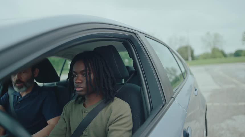 A driving instructor observes as a young man prepares to drive