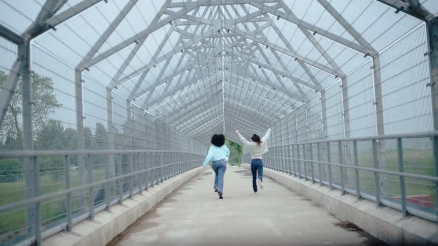 Two women running across an overpass