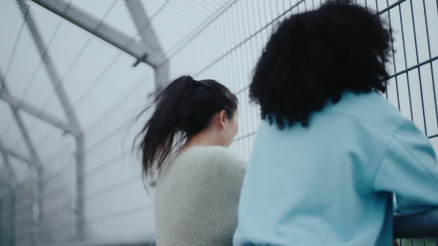 Two friends on an overpass talking happily