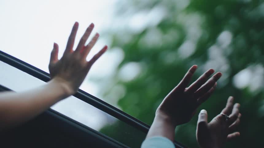 People wave their hands up out of the sunroof