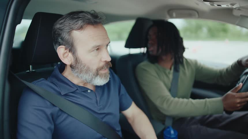 A driving instructor coaches a student inside a moving car