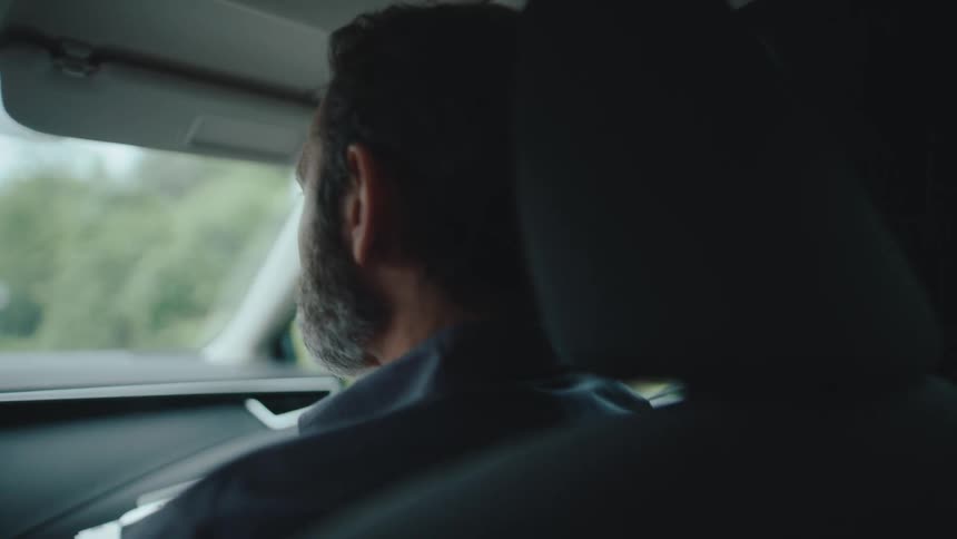 Man looks out the window while riding in a moving car