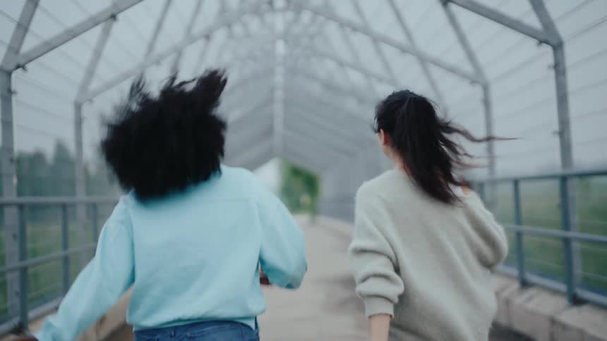 Two women walking on an overpass on a foggy day with happy body expressions