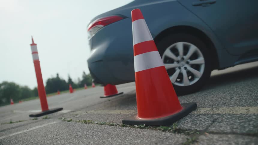 Vehicle backing up between orange traffic cones in a parking lot