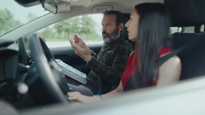 Driving school instructor talking to a student inside the car