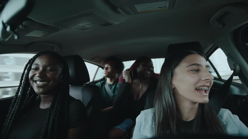 Group of happy friends inside a moving car