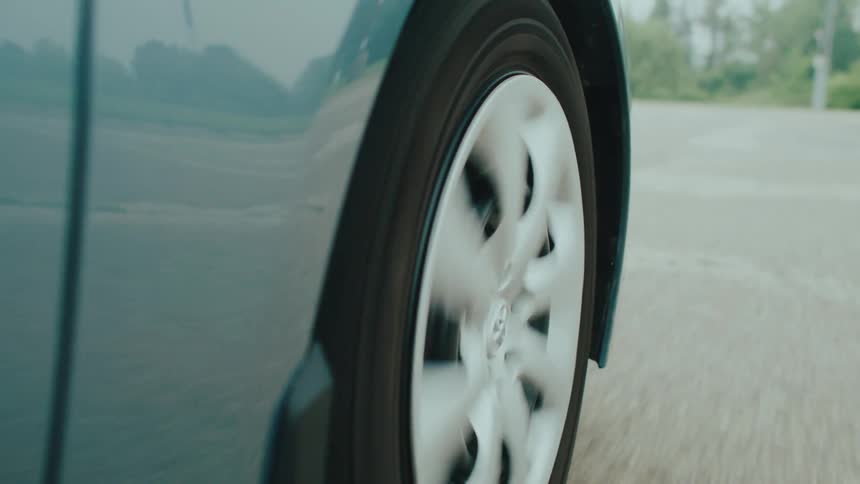 Closeup of a car wheel spinning while driving on a road