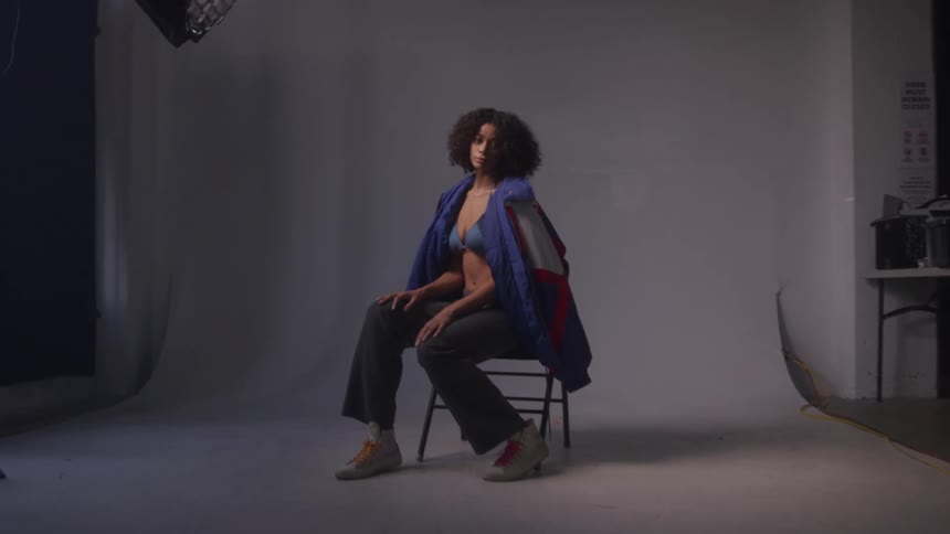 Woman sitting on a chair modeling in a studio with a white background