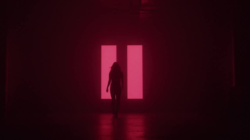 Flashing symbols of light are on the wall as the woman walks towards it
