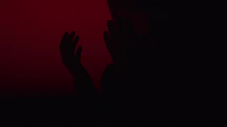 Red light is flashing symbols on the wall as a man uses a vr headset