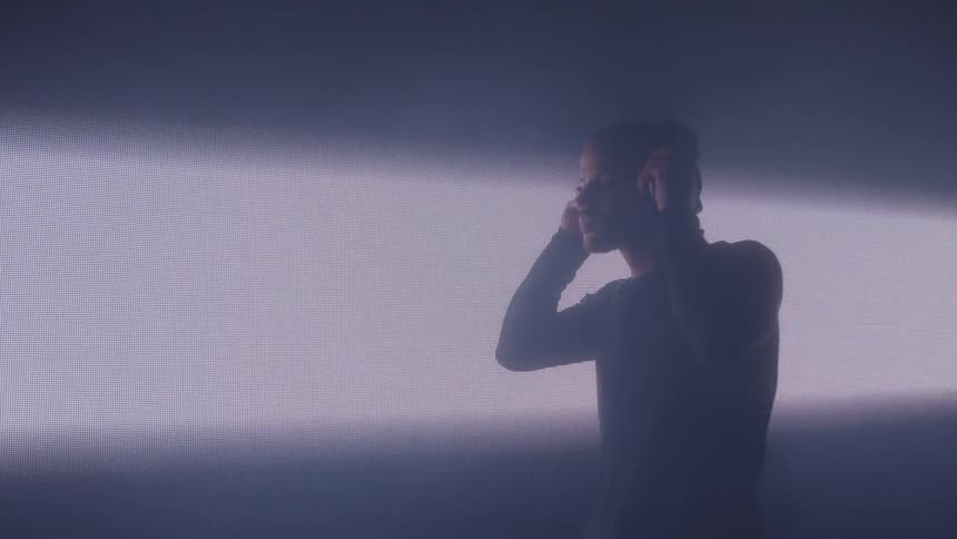 A black male with headphones on is under dramatic lighting