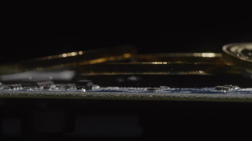 Several gold colored coins are placed atop a printed circuit board