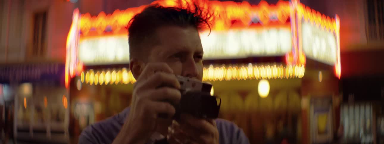 Man taking photographs in city on windy night
