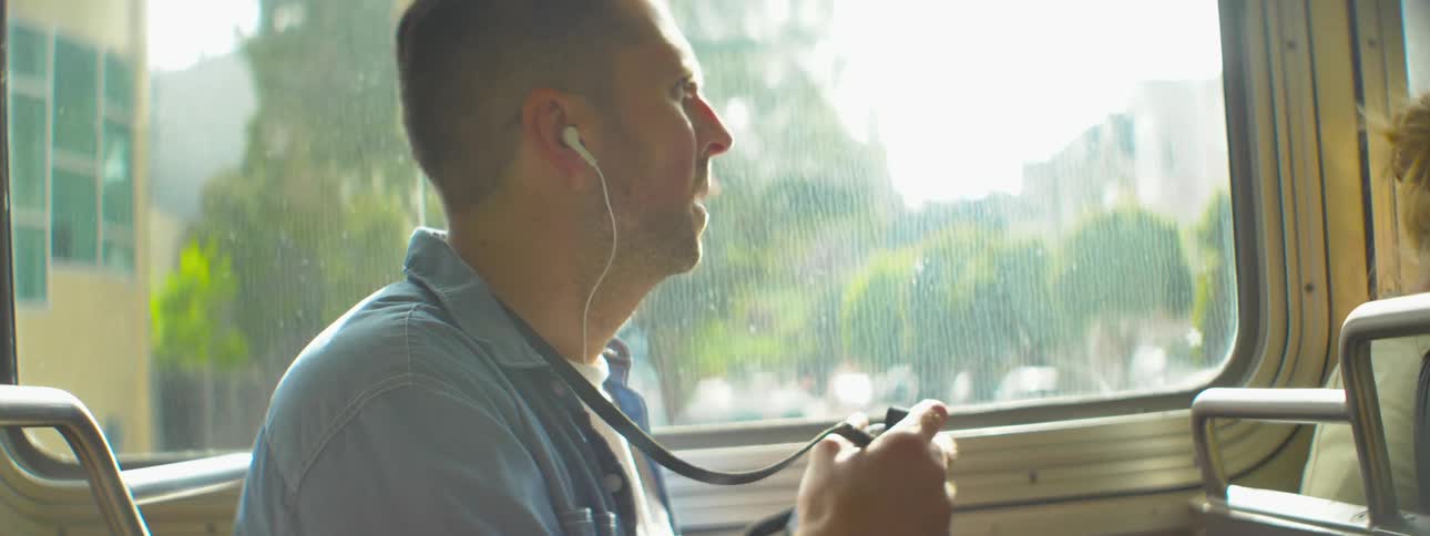 A man takes a photo from a moving bus in a city