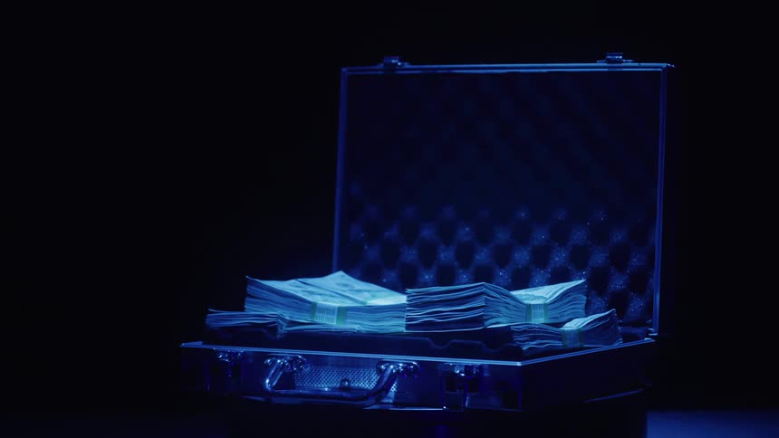 A glowing briefcase spinning filled with cash is illuminated under blue light