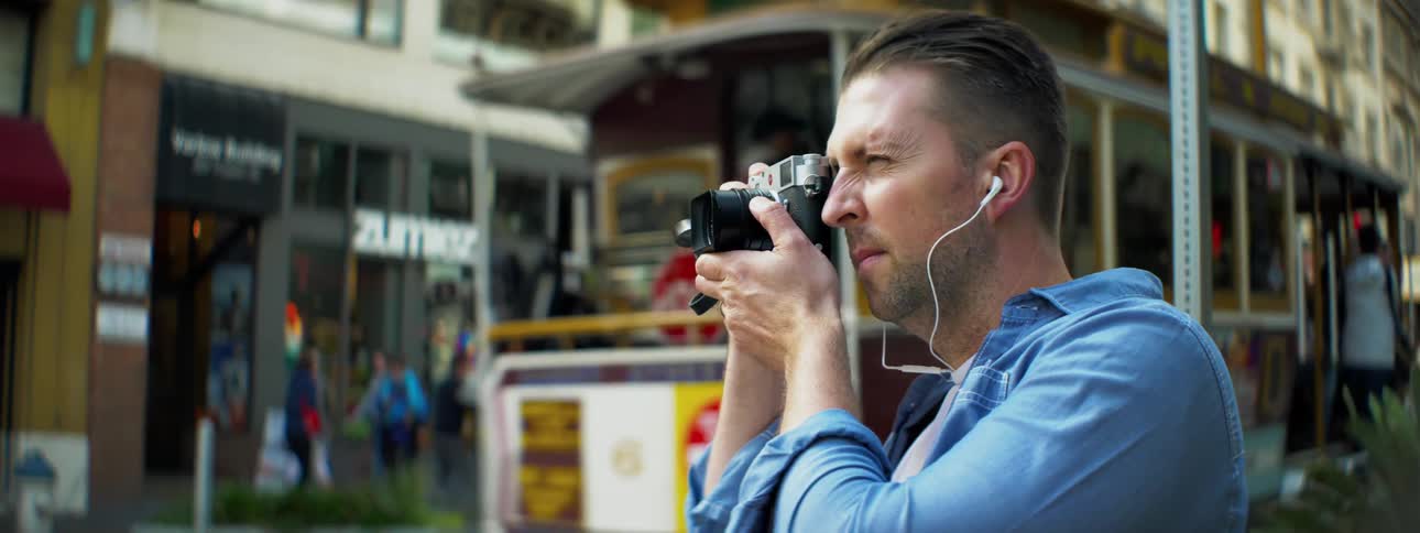 A man takes pictures while wearing earbuds