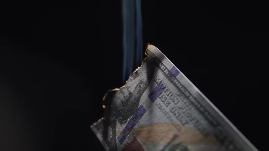 A us one hundred dollar bill is smoldering as it slowly burns