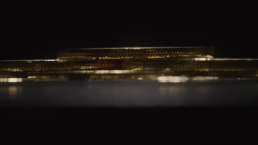 Stacked gold coins gleam under low light against a dark background
