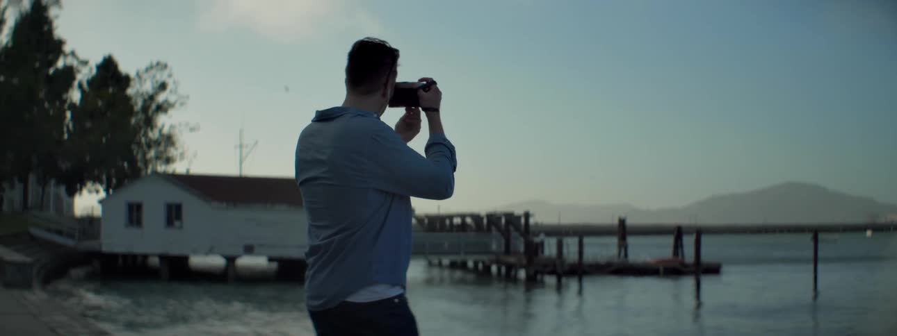 A man walks along the shore taking photographs
