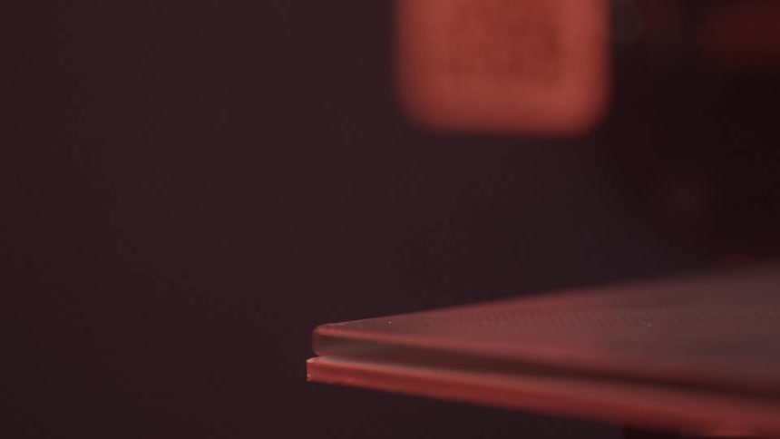 A 3d printers heated bed or nozzle is shown in closeup with warm lighting