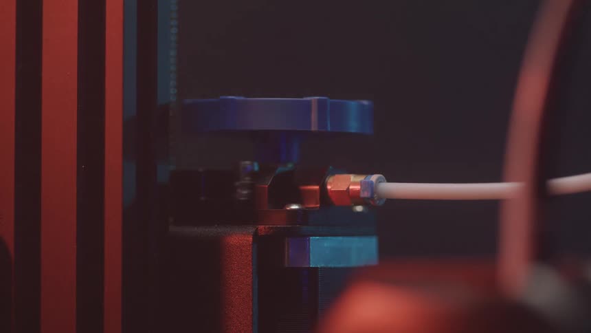 The video provides a detailed closeup of a 3d printers extruder mechanism with a white filament feeding into it the internal red light illuminates the process showcasing the precision and movement involved in preparing to print
