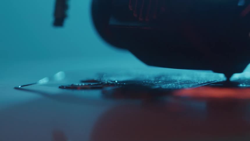A 3d printer head extrudes filament while printing a layered object in a closeup shot