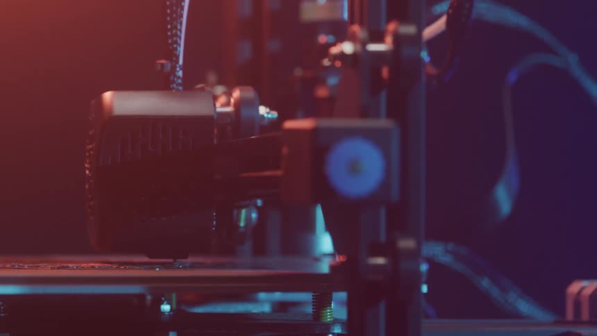 A 3d printer head is actively printing an object in a dimly lit workspace