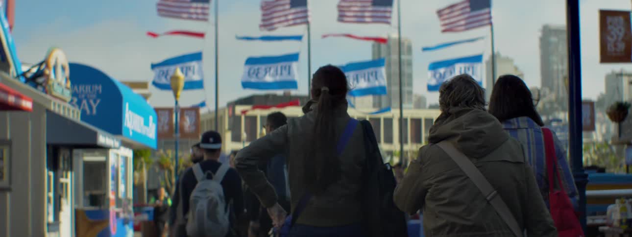 People walk near billowing flags in a city