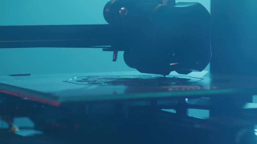 A 3d printer precisely layers material in a bluelit workspace