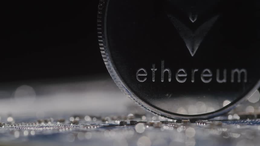 Close up of a physical ethereum coin placed vertically on a circuit board in a dark room