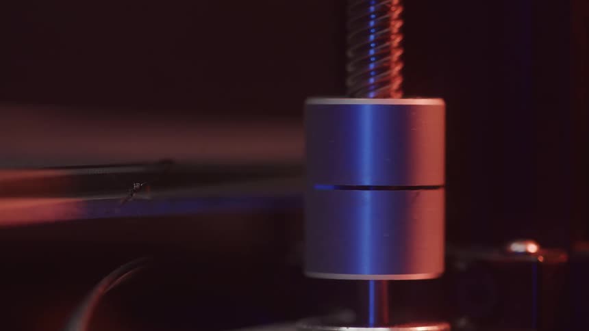 A machine glows under dramatic lighting in a dark industrial setting