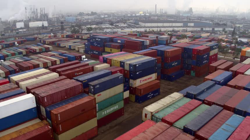 Rows of colorful shipping containers fill a busy industrial port