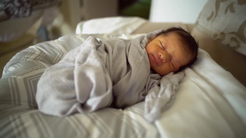 Newborn baby wiggling in blanket as it sleeps