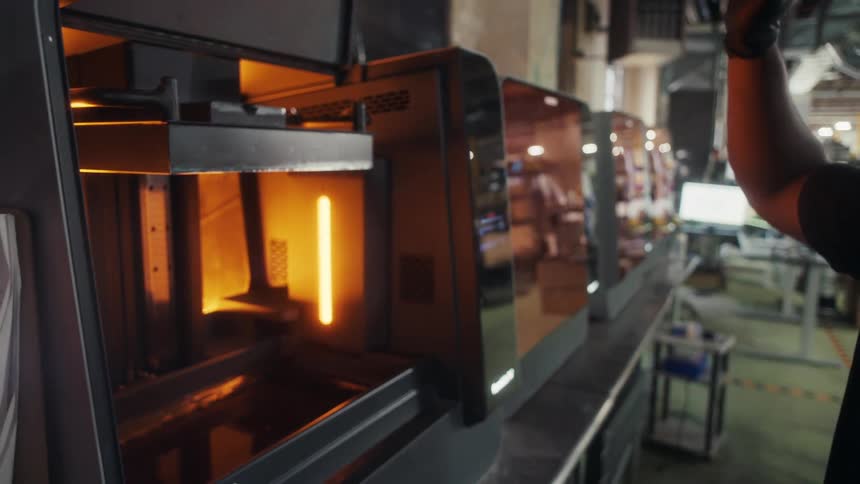 A person is pressing a button on a machine likely starting or controlling the 3d printing process